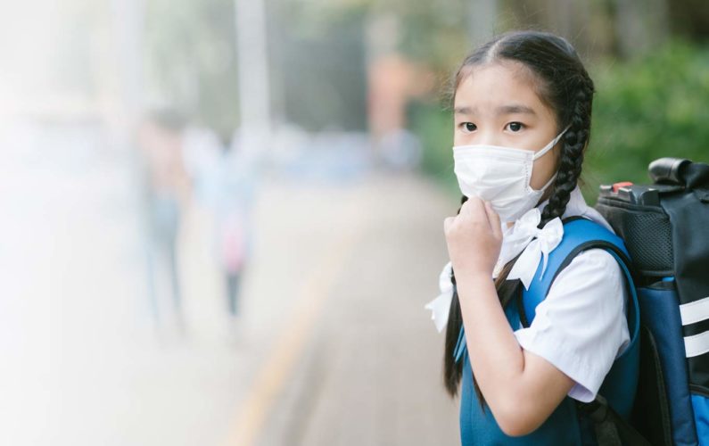 Jeune écolière portant un masque contre la pollution