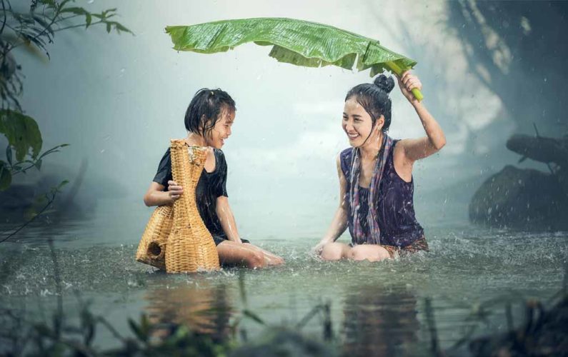 Femme et enfant souriants sous la pluie