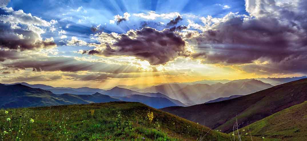 Nuages et rayons de soleil sur collines verdoyantes