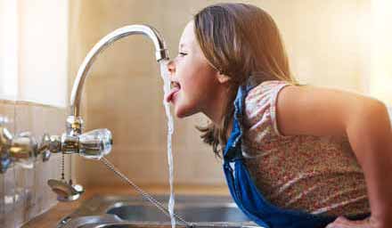 L'eau de boisson, filtrée et vitalisée bue par une enfant au robinet