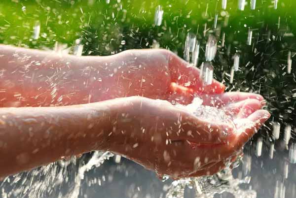 Mains tendues recevant de l'eau de pluie